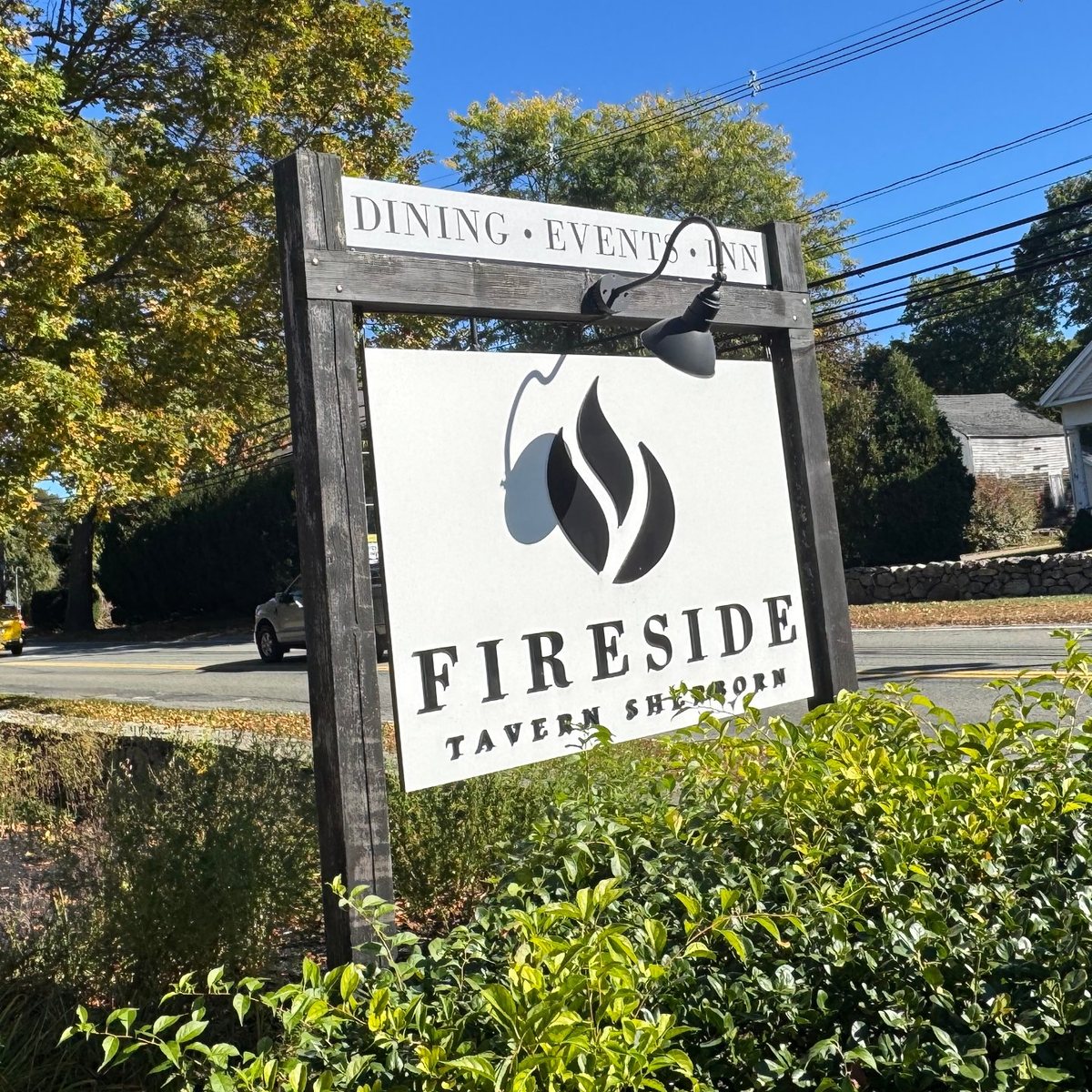 The Fireside Tavern sign, with its flame logo and “Dining · Events · Inn,” beside North Main Street in fall