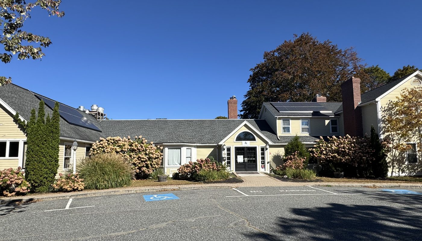 The front entrance of Fireside Tavern, a long yellow clapboard building with hydrangeas along the walk