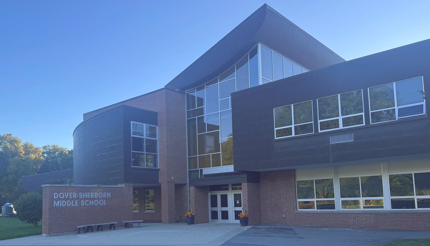 Dover-Sherborn Middle School, a brick and glass building with a curved roofline and its name on a brick wall beside the front entrance