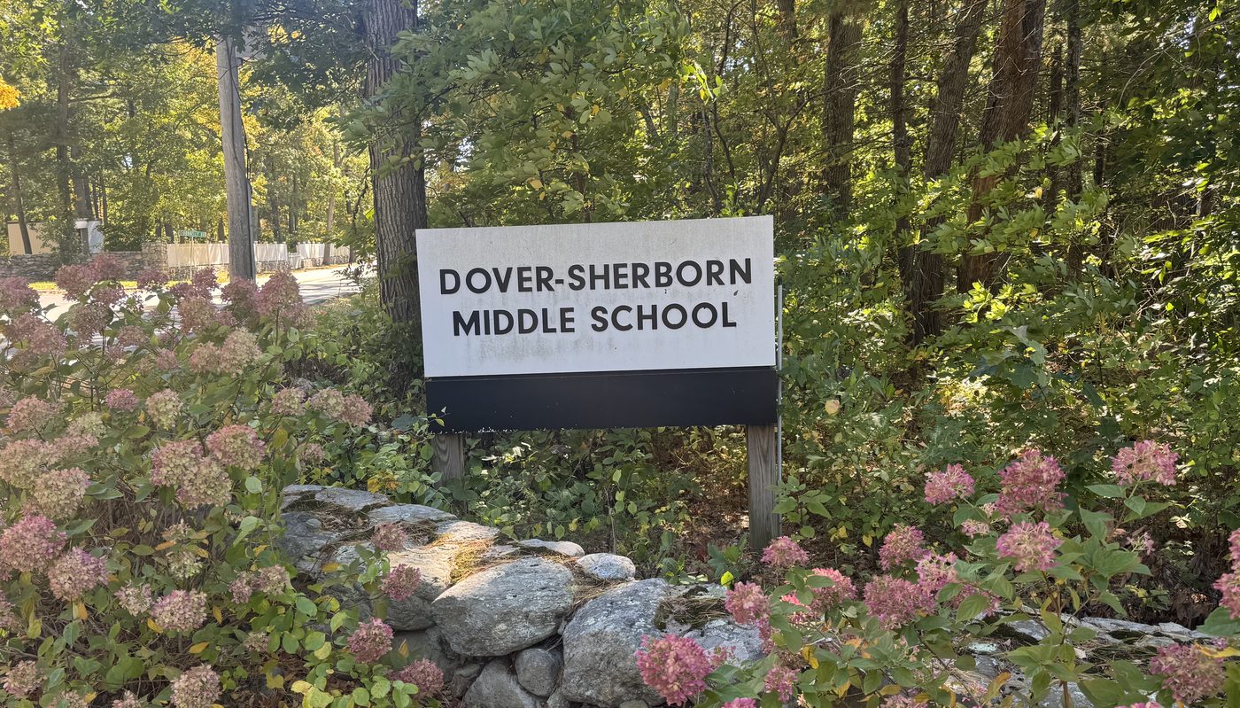The Dover-Sherborn Middle School sign behind a stone wall and pink hydrangeas
