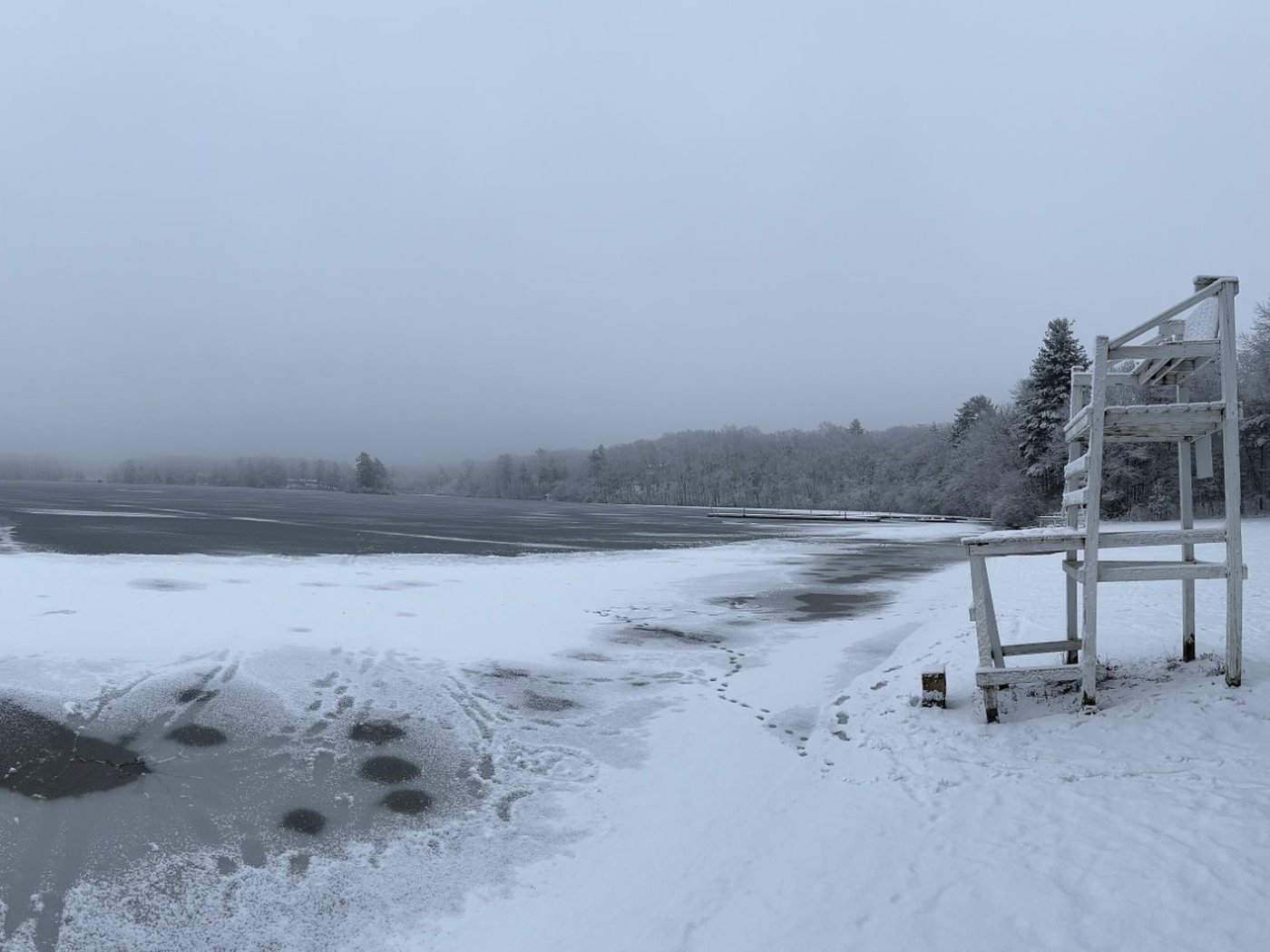 Snow-covered shoreline and a lifeguard chair at Farm Pond in winter