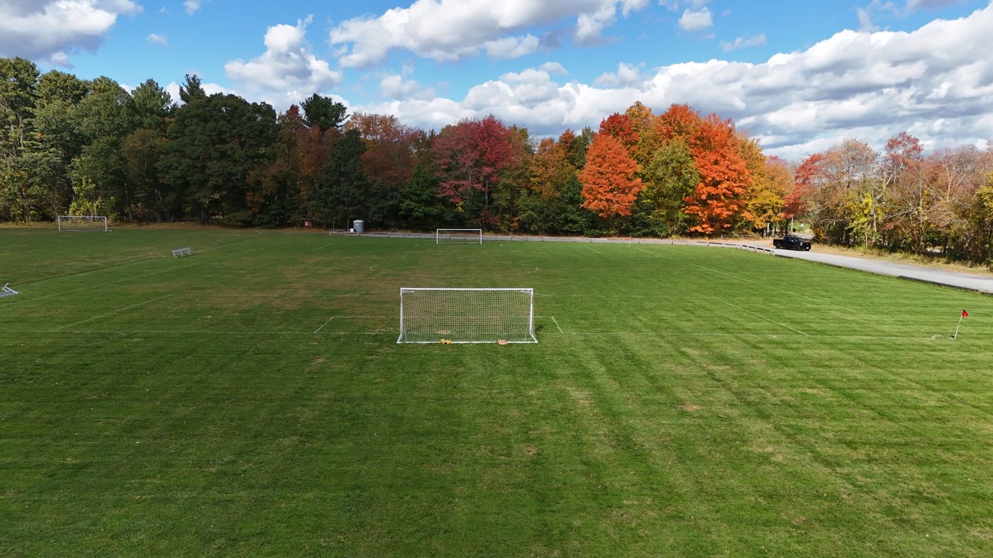 The soccer fields at Fessenden in fall, with a goal in front and red and orange trees along the edge