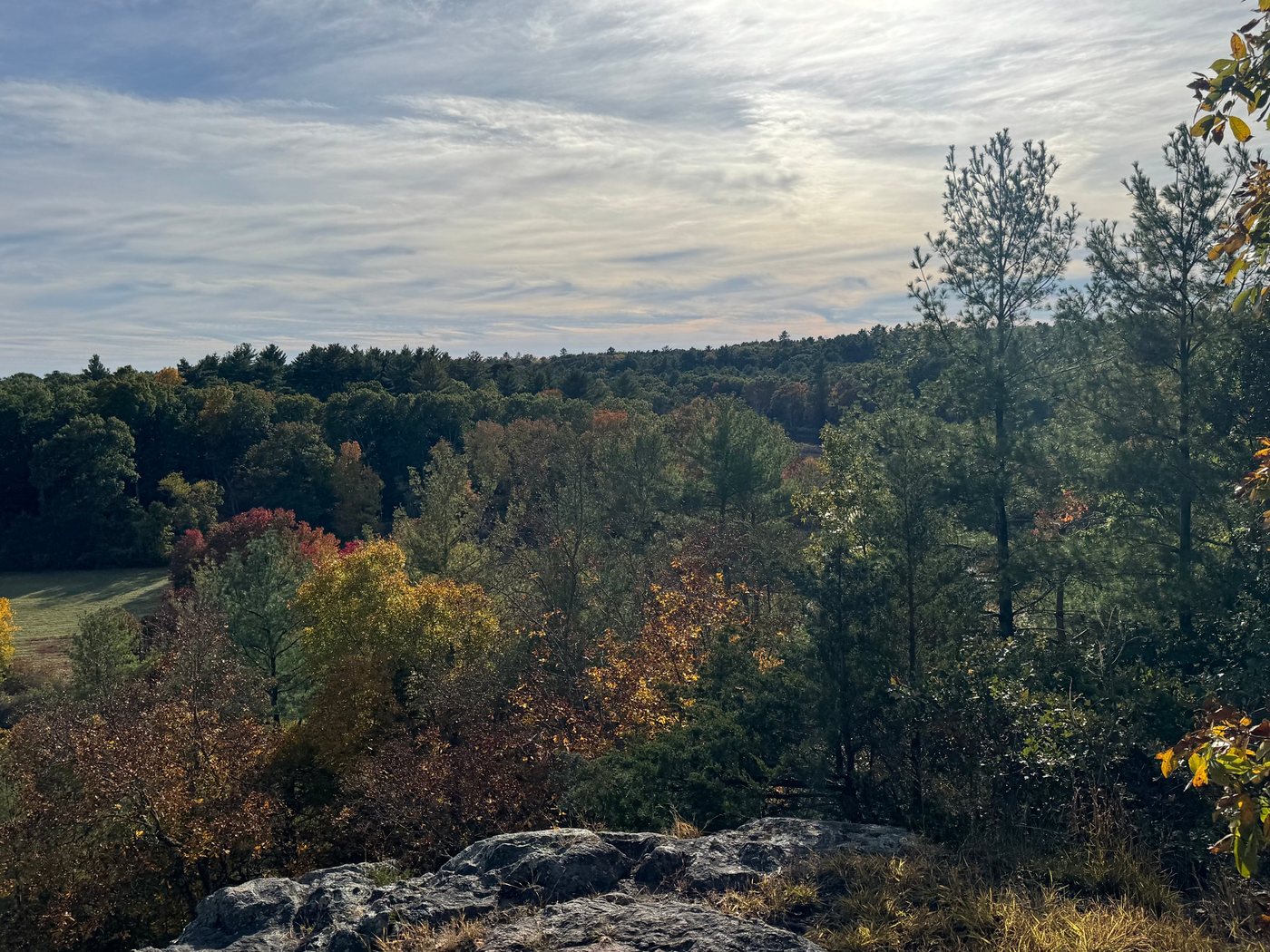 The view from the granite ledge at King Philip’s Overlook in fall, looking out over red and gold trees and a distant field