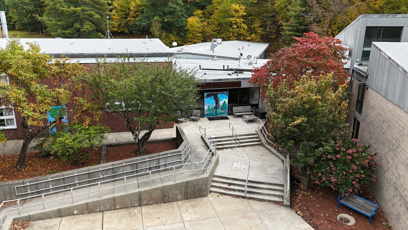 Pine Hill School’s entrance courtyard from above, framed by red and gold fall trees