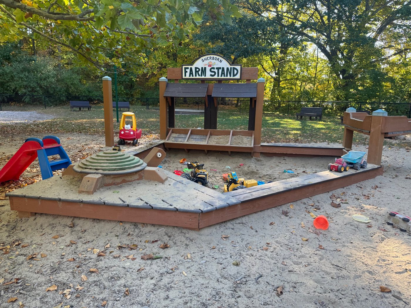 The sandbox at Sherborn Playground, built around a Sherborn Farm Stand sign and a wooden turtle