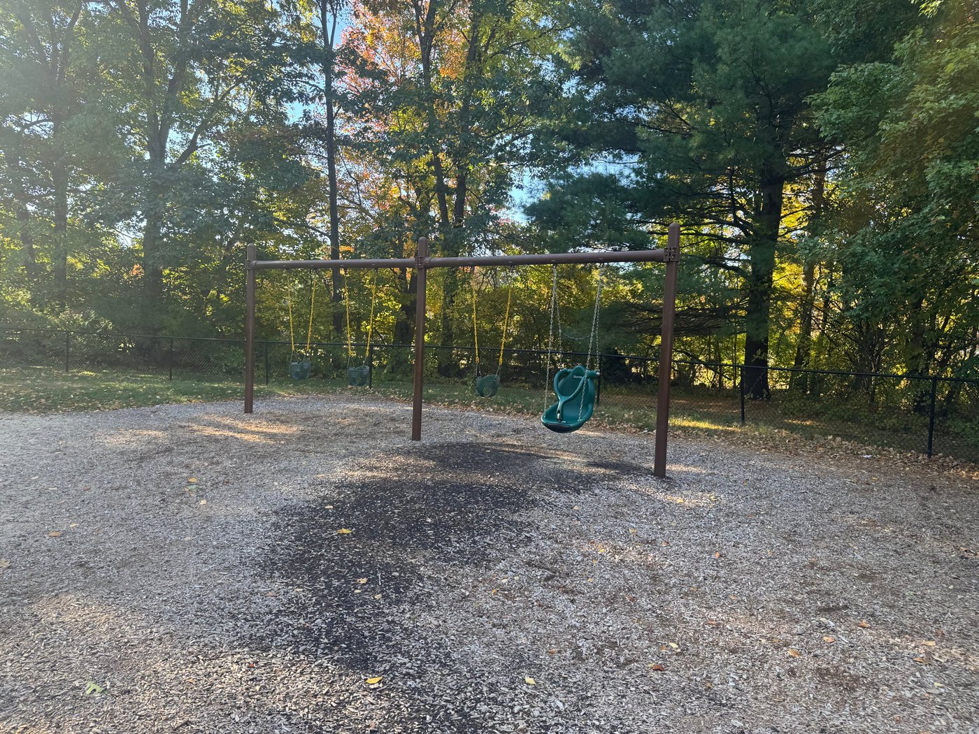 The swing set at Sherborn Playground, with bucket swings and a green high-back support swing