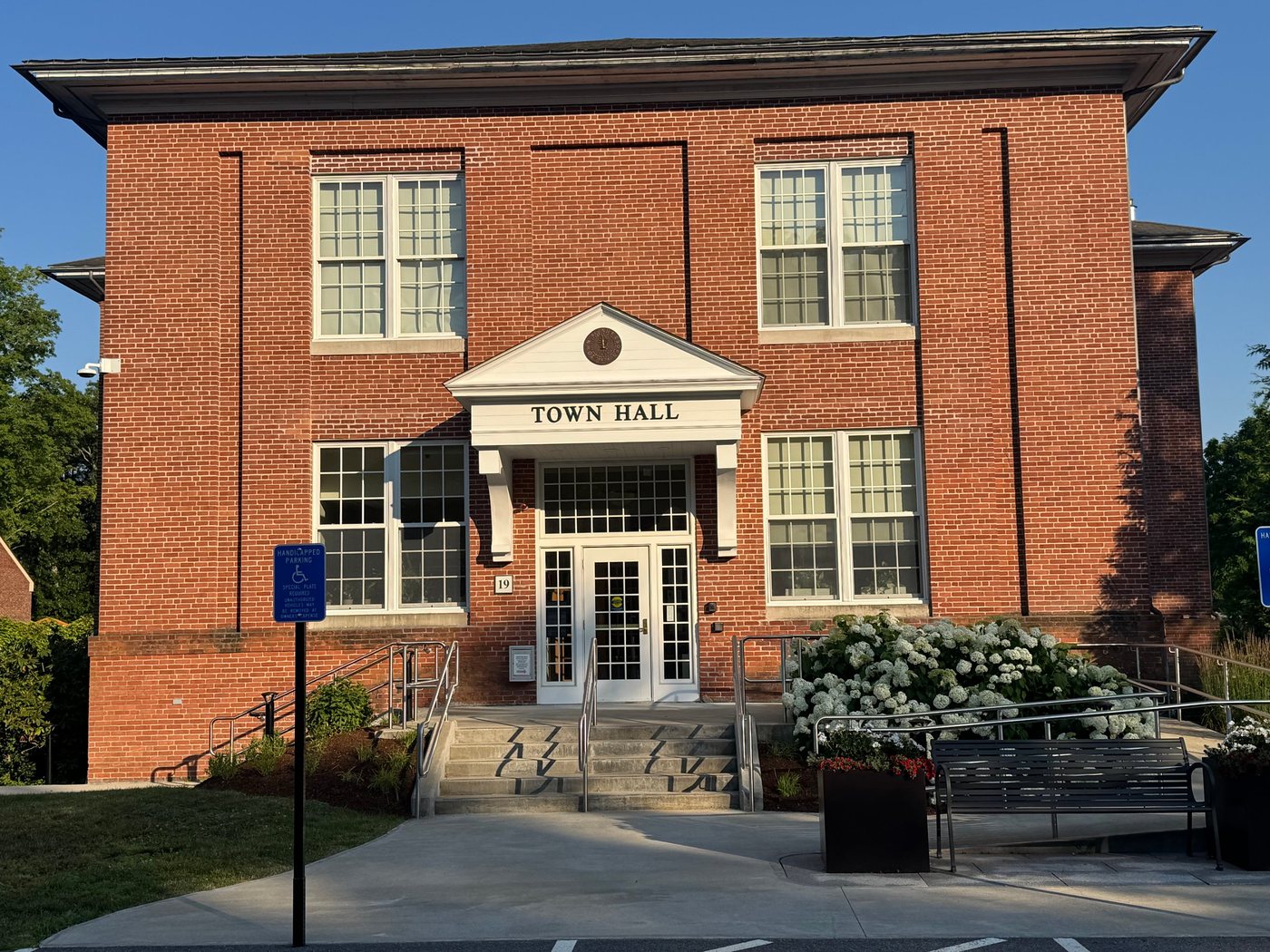 Sherborn Town Hall, a two-story red brick building with a white pedimented entry, on a summer evening